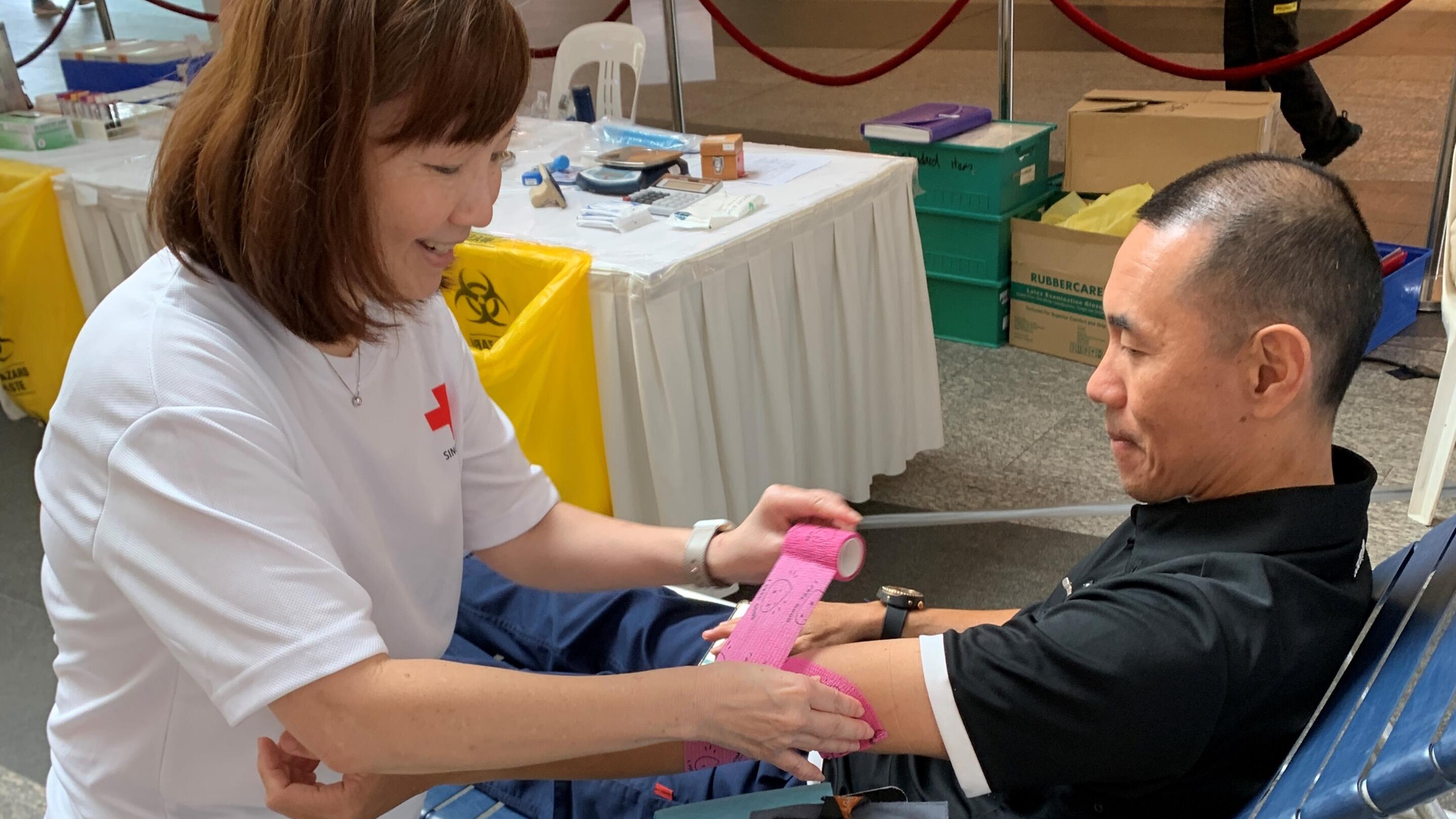 ExxonMobil colleague bandaging the arm of blood donor at the ExxonMobilSG drive