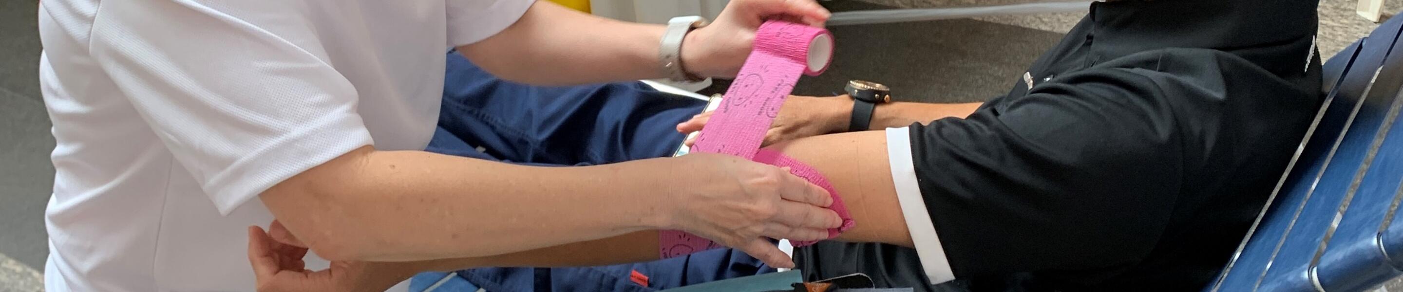 ExxonMobil colleague bandaging the arm of blood donor at the ExxonMobilSG drive