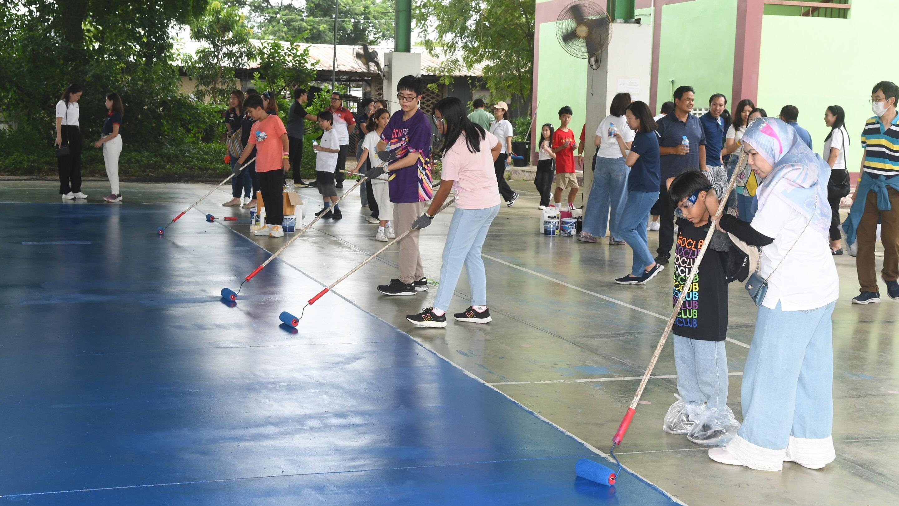 Volunteer employees and their families painting the volleyball court.
