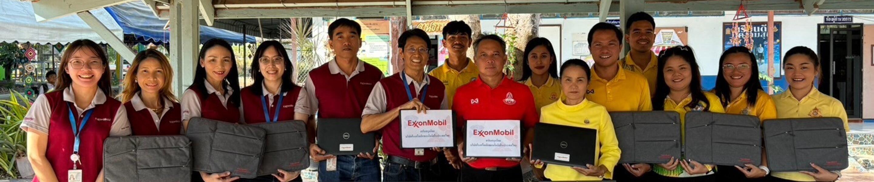group photo of ExxonMobil affiliate staff representatives and school recipients holding laptops donated