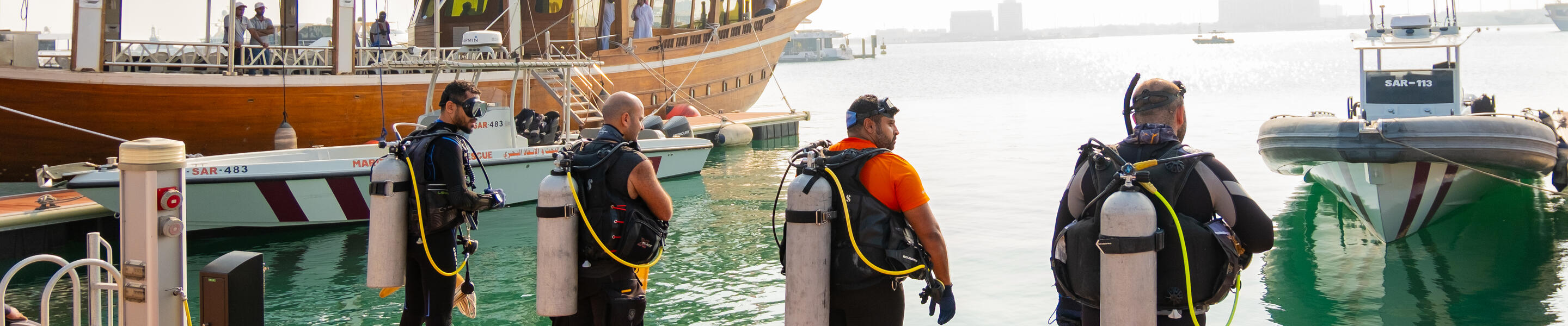 Divers before they entered the waters of Old Doha Port to  begin removing harmful debris.