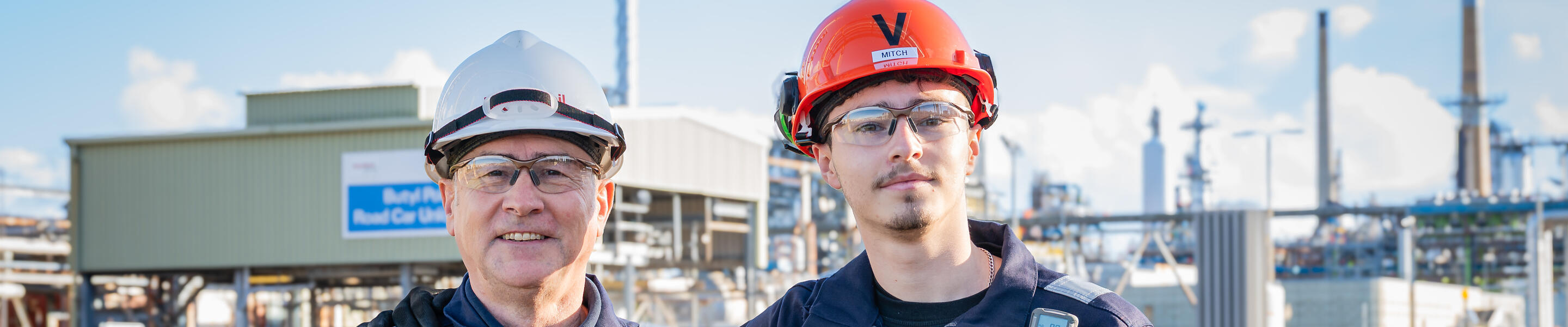 ExxonMobil Fawley (United Kingdom) employees Andrew and Mitchell Mcphee wearing protective gear and standing in front of complex