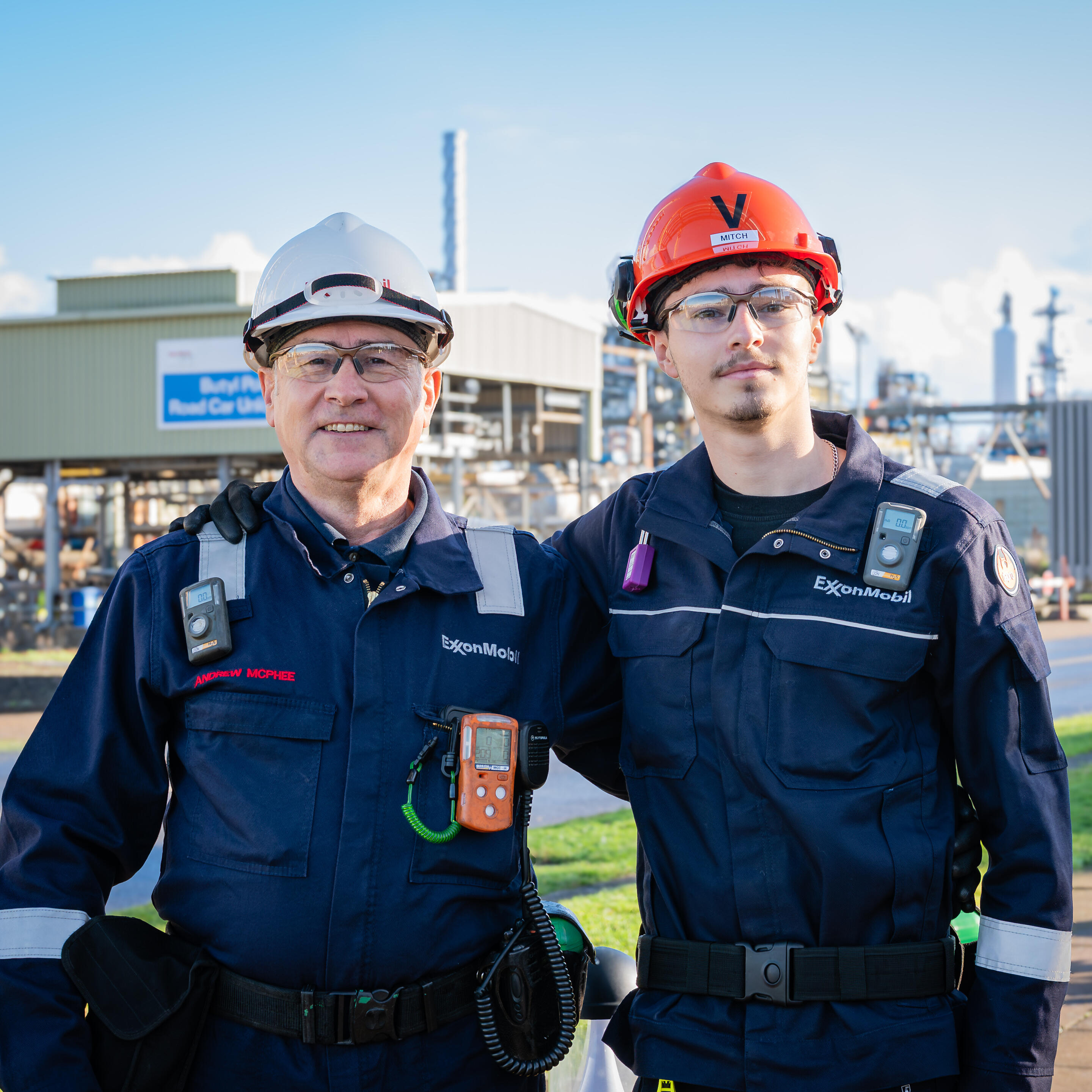 ExxonMobil Fawley (United Kingdom) employees Andrew and Mitchell Mcphee wearing protective gear and standing in front of complex