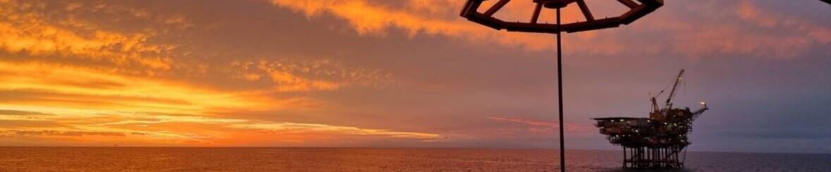 oil platform in the ocean with sunsetting in background