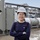 A person standing with arms crossed in an industrial setting.