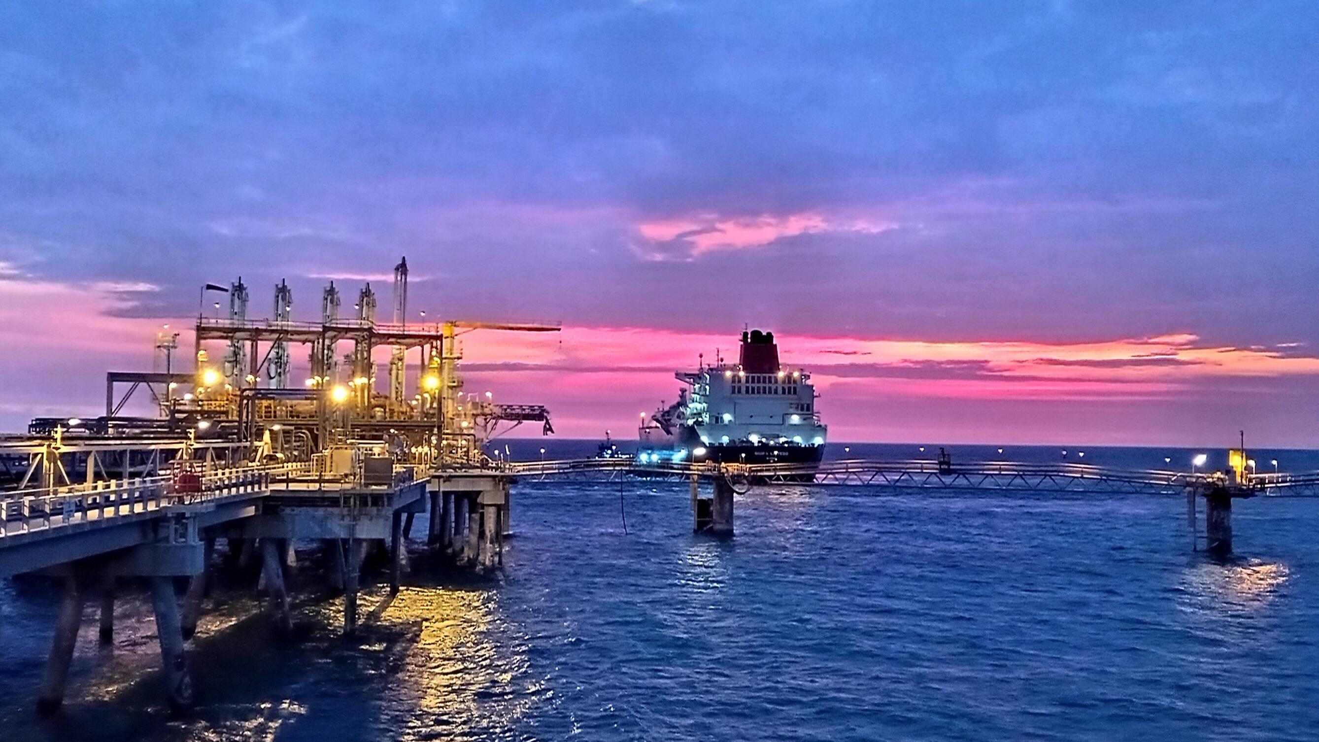 port with ship approaching at sunset