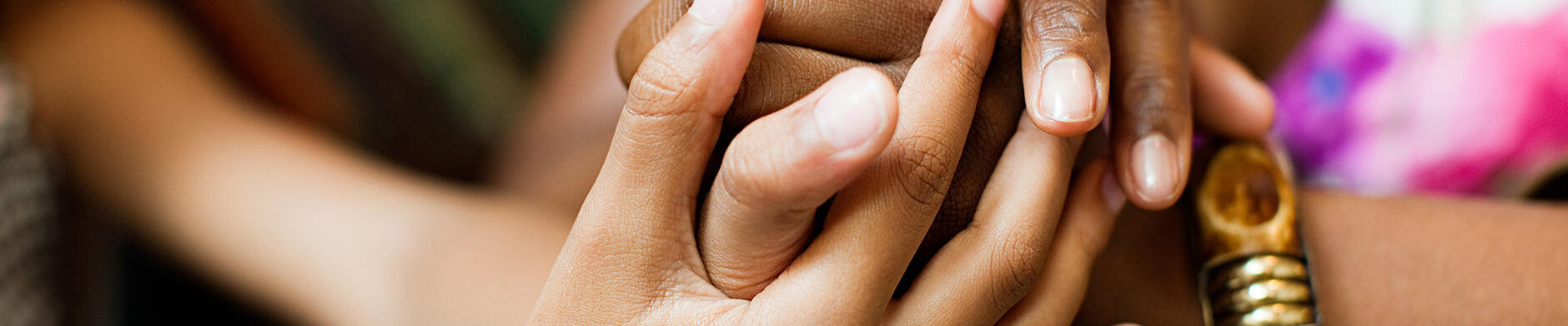 Two pairs of hands gently holding each other.
