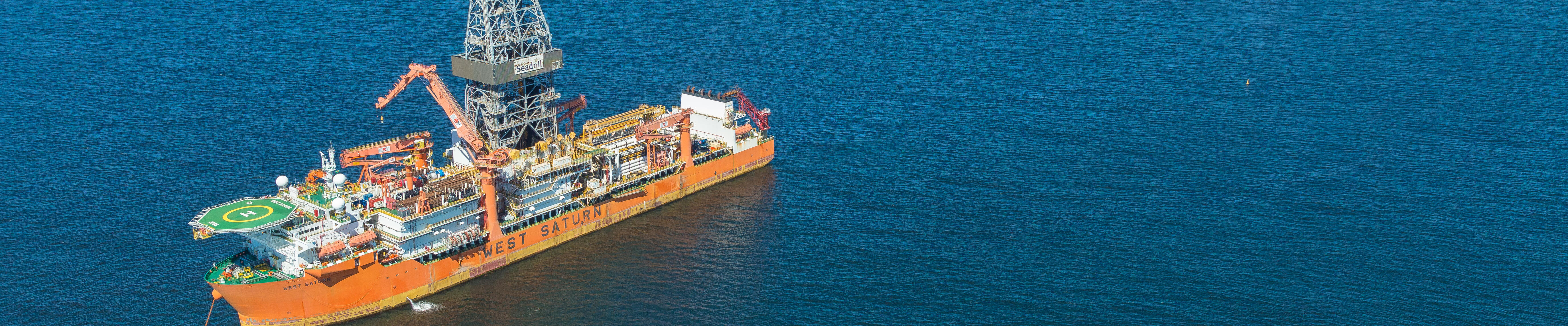 offshore oil drilling vessel with tropical-looking land in the background