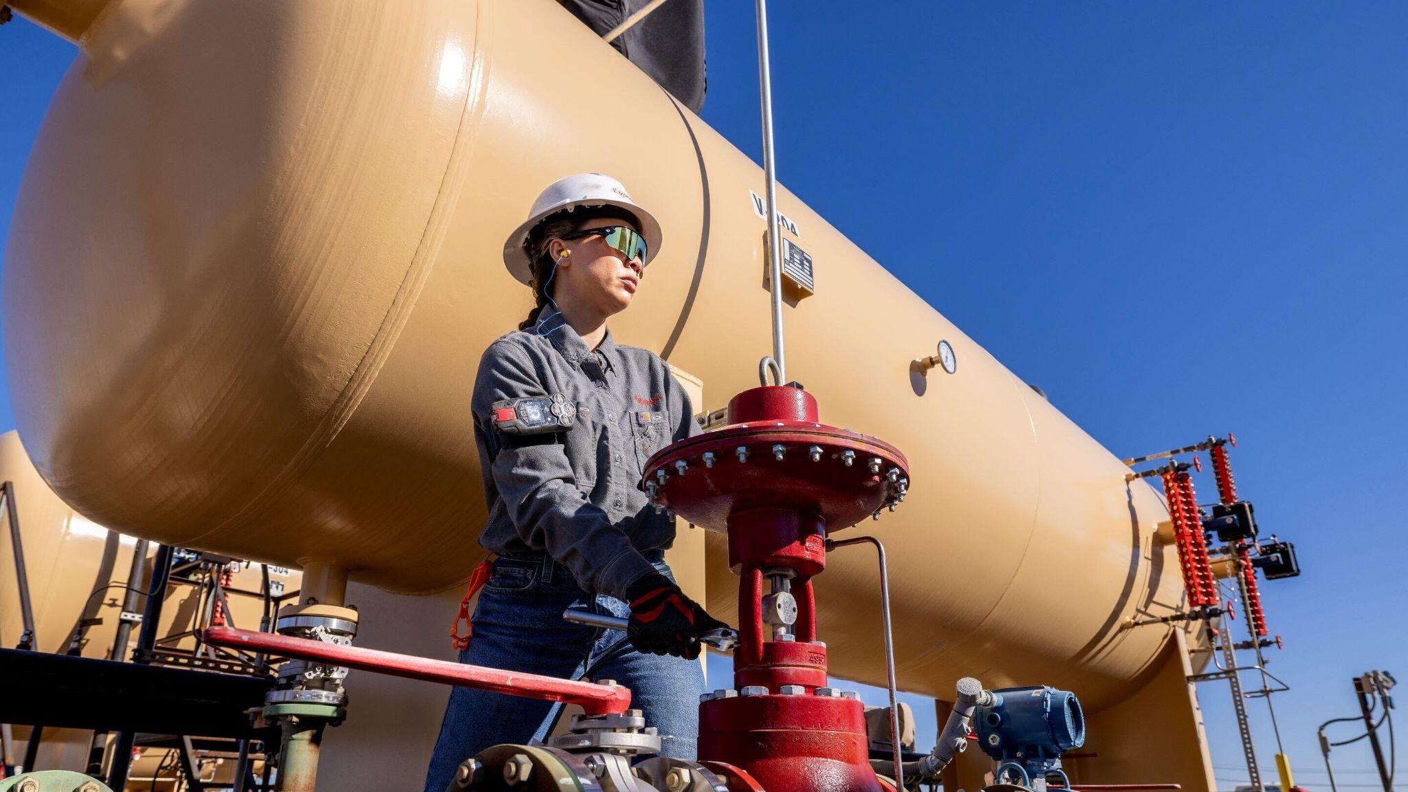 ExxonMobil Permian Basin female employee adjusting a valve at pipe