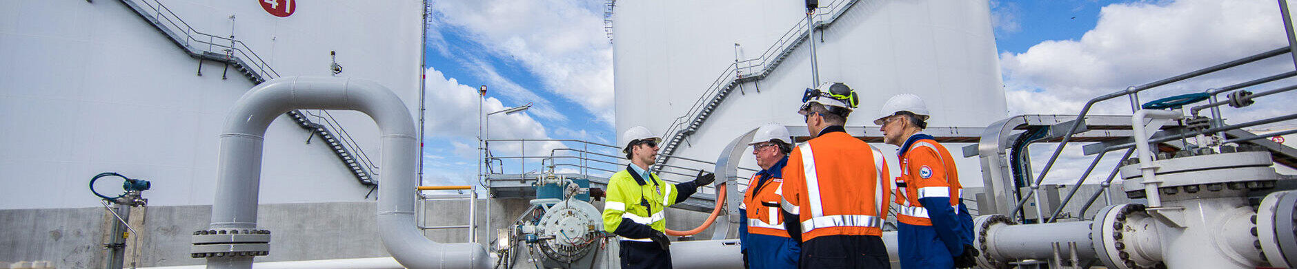 workers standing in front of storage tanks at ExxonMobil Australia's Yarraville terminal