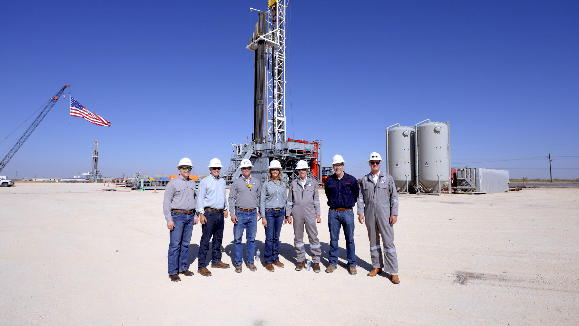 Group of ExxonMobil employees standing near a drilling rig.