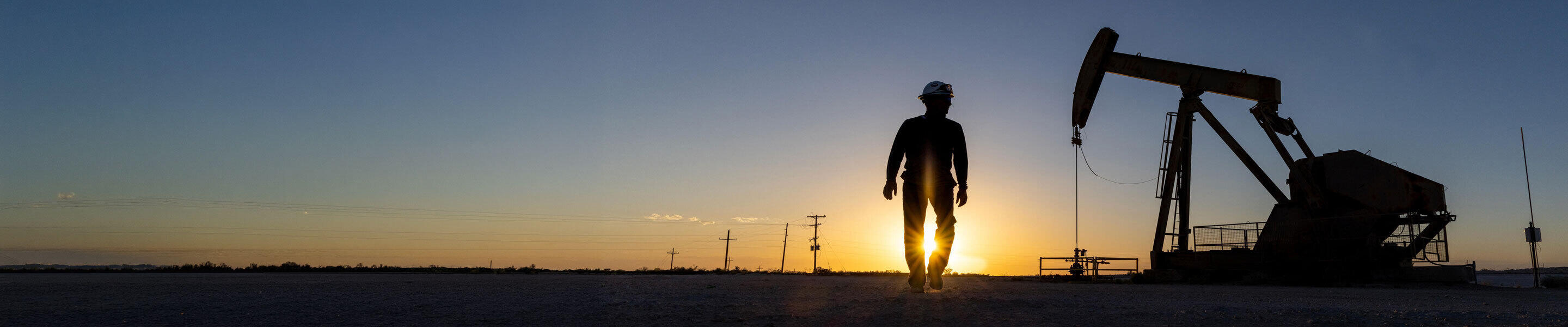 ExxonMobil employees working new a pump jack at dusk.