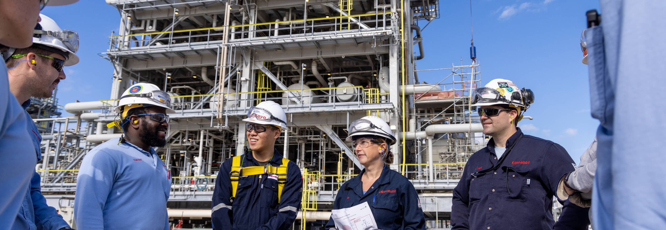 ExxonMobil team standing outside an oil rig talking.