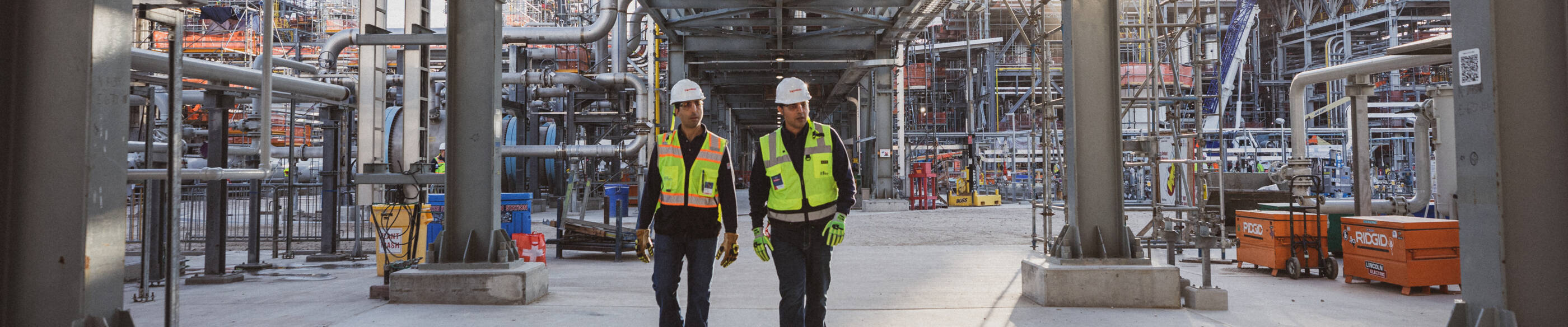 Two employees in safety equipment walking in the Baytown facility