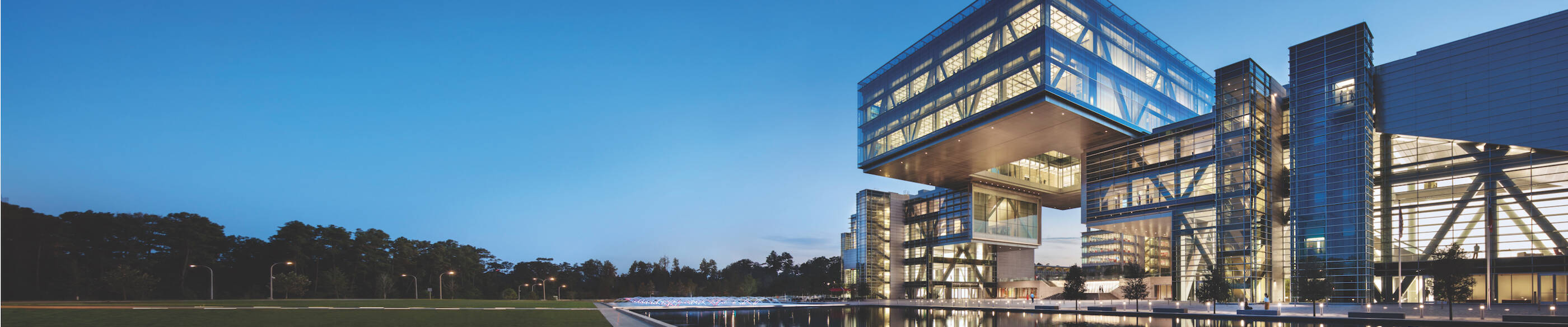 A photo of a glass building (the Cube) during sunset overlooking a pond