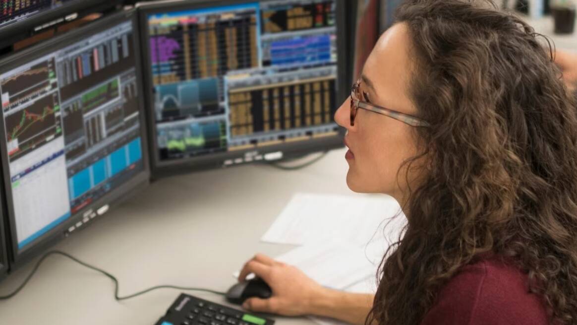Women looking at multiple computer monitors.