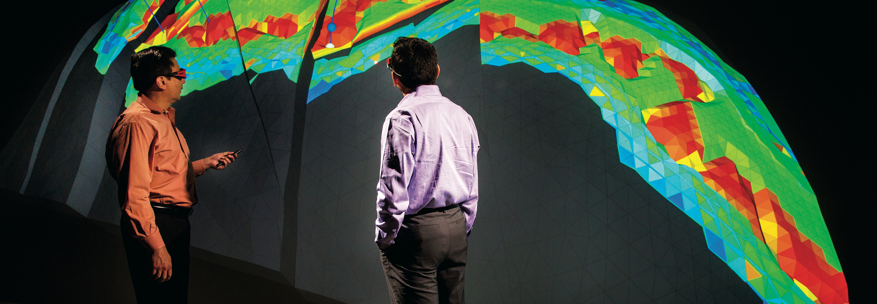 Two men stand in front of seismic imaging readout