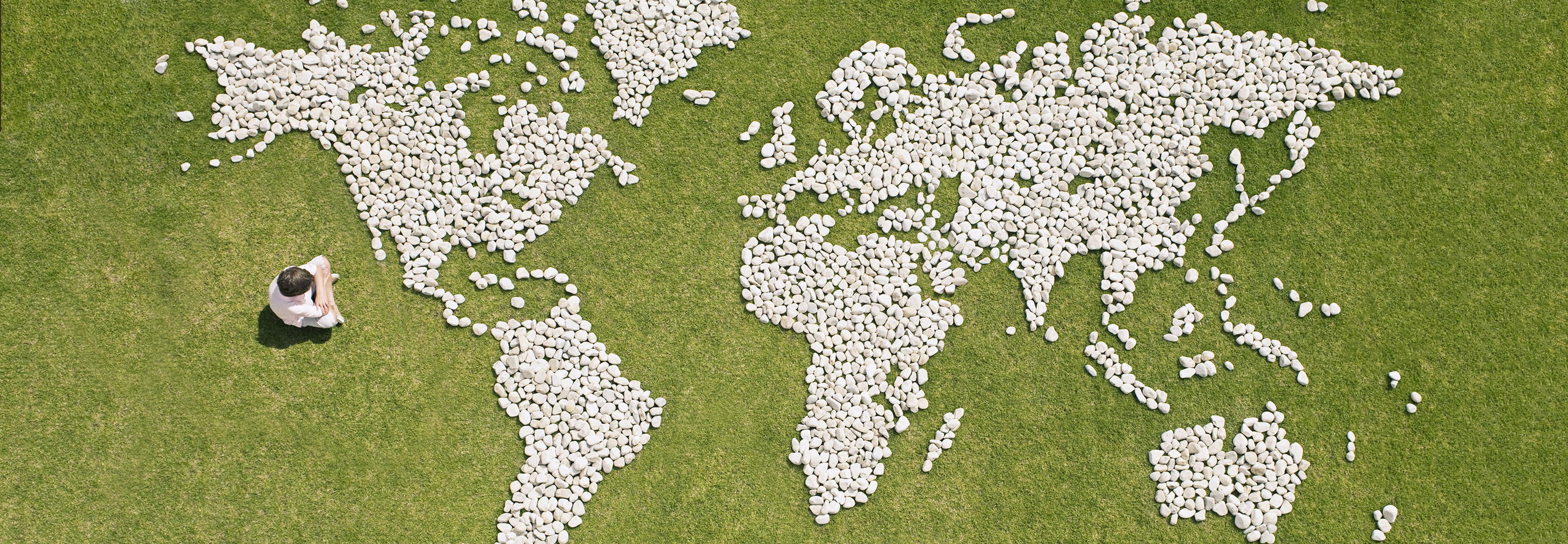 A boy sitting in front of a world map made from stones