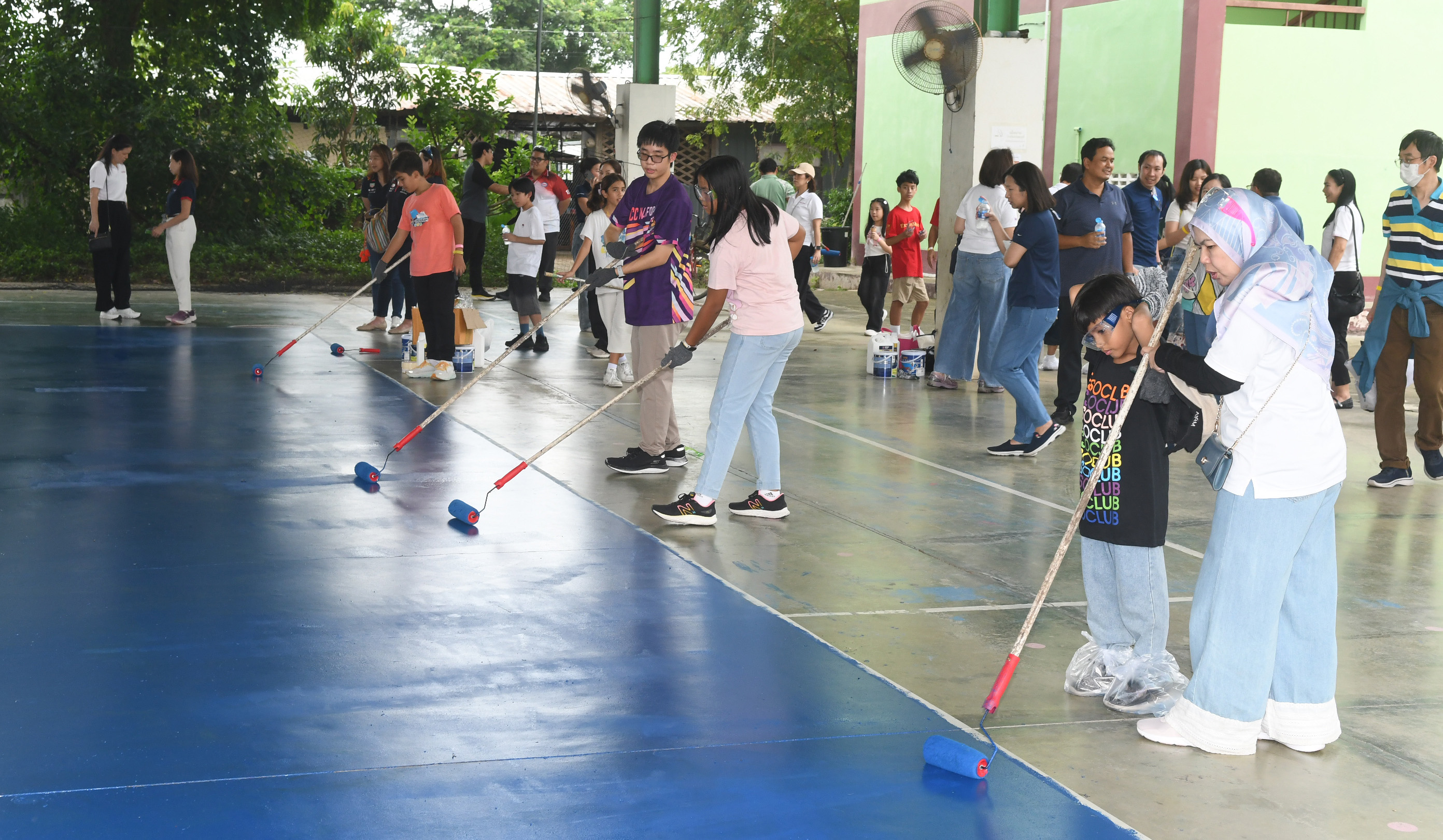 Volunteer employees and their families painting the volleyball court.