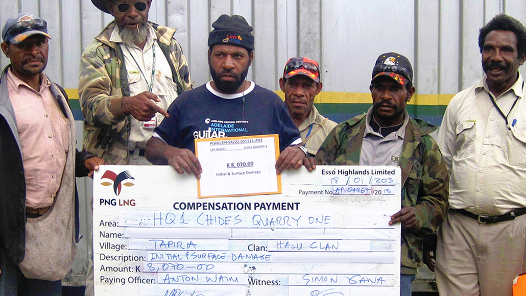 Local community members with a compensation payment check