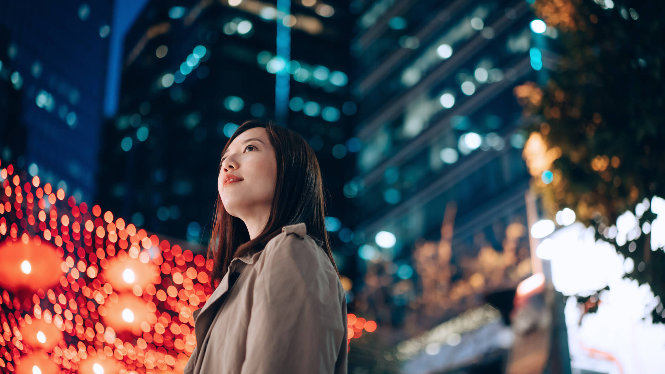 Asian woman in front of city lights at night. 