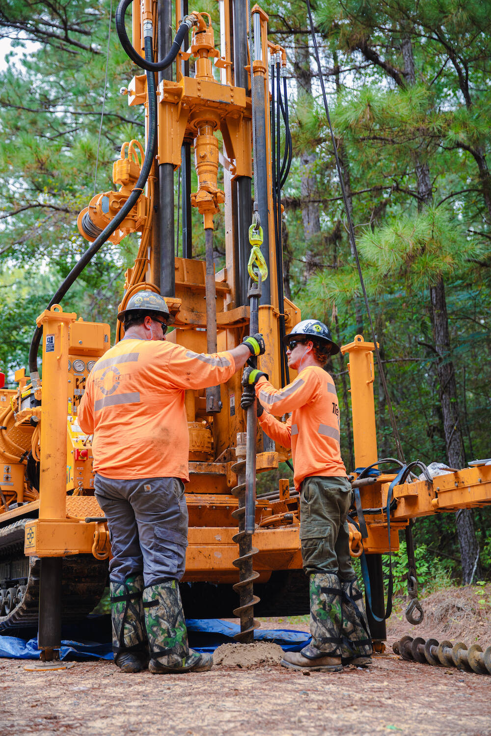 Two workers wearing orange shirts and hard hats.