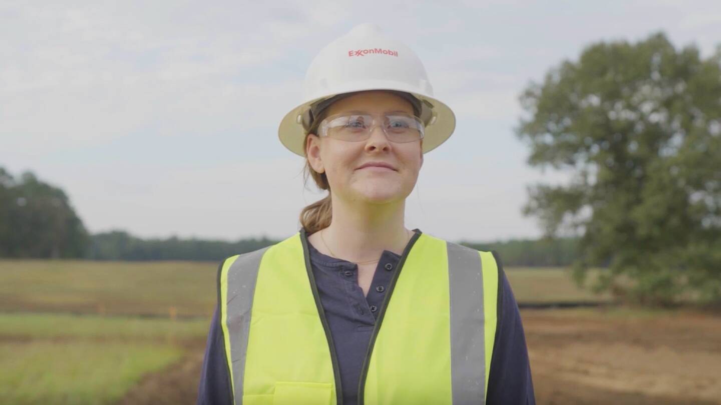 Female worker wearing safety vest, goggles and hard hat.